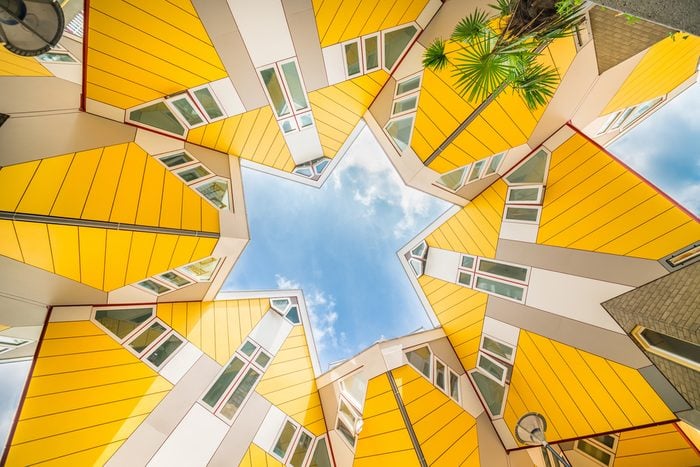 Star shapes formed where six Cube houses tilt into one another and intersect in Rotterdam, a quirky bright yellow architecturally unusual angular cube shape apartment block