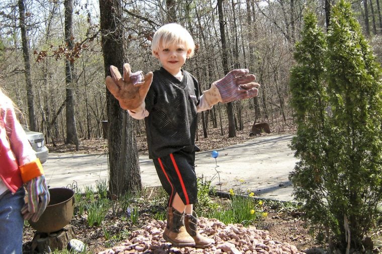 grandson playing in dirt with gardening gloves