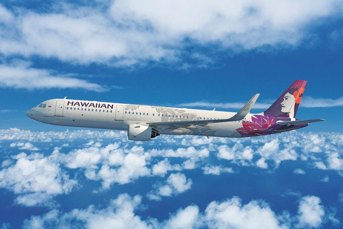 Hawaiian Airlines Airplane In Flight among clouds and blue sky