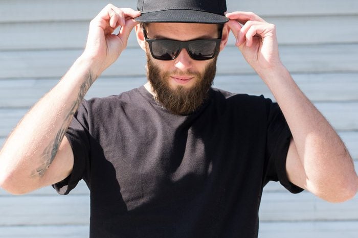 Hipster man wearing black T-shirt and a black hat with space for logo