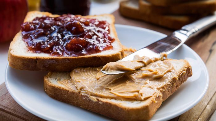 Peanut butter and raspberry jelly sandwich on wooden background. Perfect sweet breakfast. Close up.