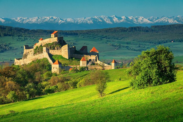 Famous Rupea fortress, spectacular fortification and high snowy mountains in background, Brasov, Transylvania, Romania, Europe