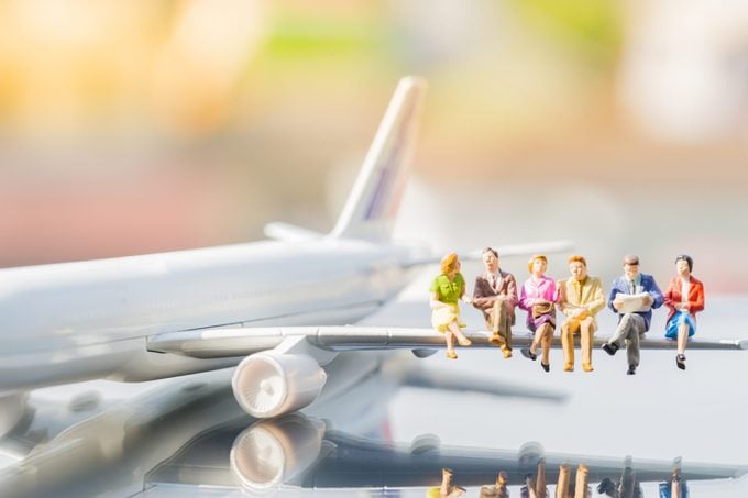 Miniature people : business team sitting on airplane wing for travel around the world, using as business trip traveler adviser agency or explorer on earth background concept.
