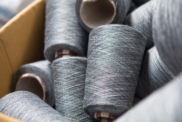 Close up gray silver yarn threads spools bobbin tubes