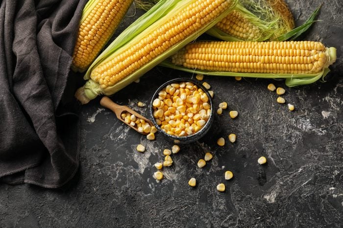 Composition with fresh corn cobs on dark background