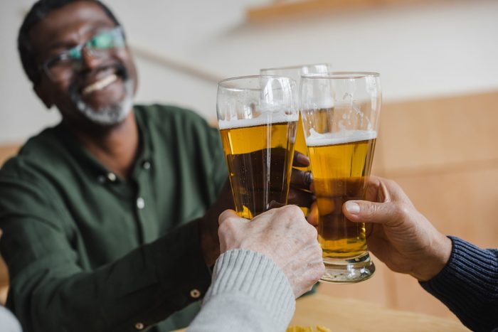 mature african american man clinking glasses of beer with friends