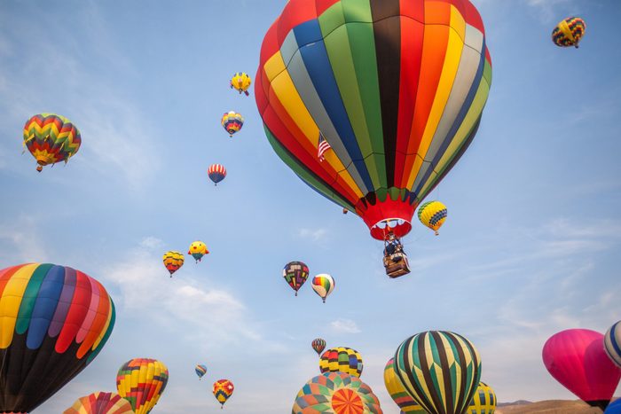 Soft-focused hot-air balloons with blue sky and clouds background