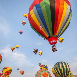 Soft-focused hot-air balloons with blue sky and clouds background