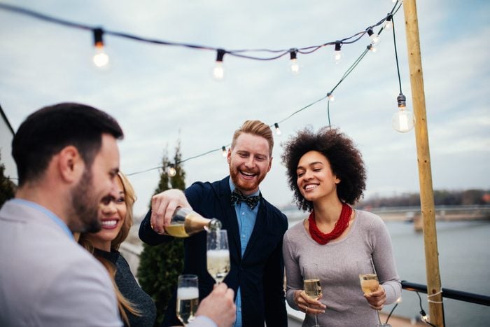 Friends celebrating on rooftop and drinking champagne