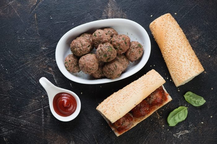 Baked beef meatballs and homemade sub sandwiches. Flat-lay on a dark brown stone surface