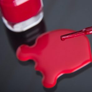 close up of the brush of a nail polish with poured nail polish and glass flask