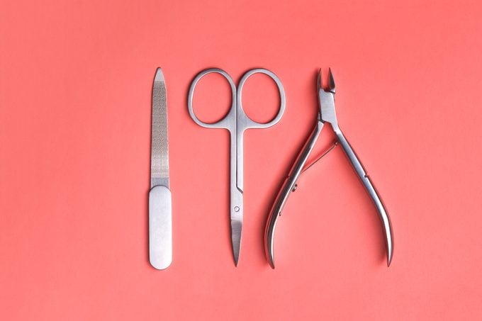 Various elegant manicure tools arranged on Living Coral background. Nail clipper, scissors and file. Color of the year 2019 concept.