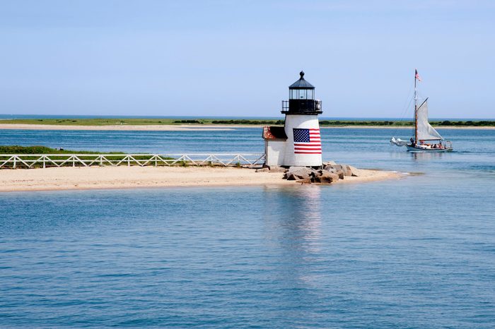 Sailing past Brant Point lighthouse on Nantucket Island on a warm quet summer day in New England.