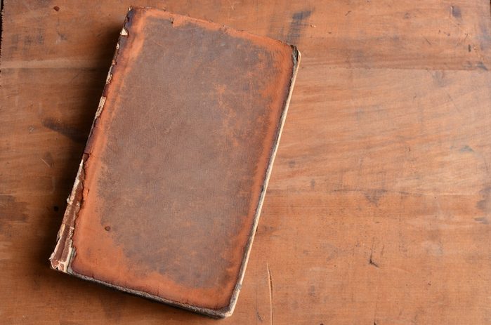 Tan vintage leather bound book laying on old rustic wood