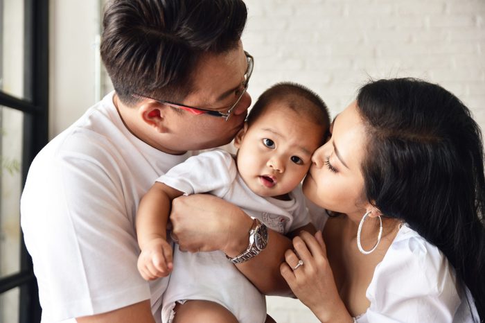 Asian woman and man kissing their baby with love.Mother and Father with lovely son.Happy family concept in house.Love and relationship idea.Warmness and happiness.Parent with little boy.
