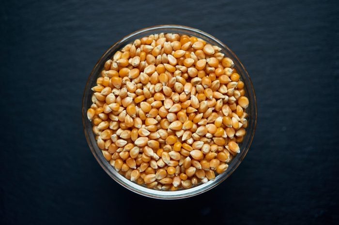 Corn seeds in a bowl on dark background. Vegetarian organic food.