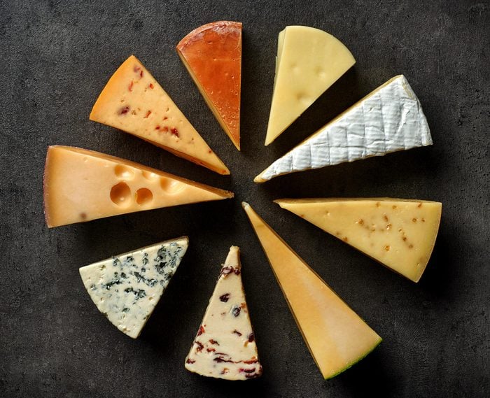 various types of cheese on black kitchen table, top view