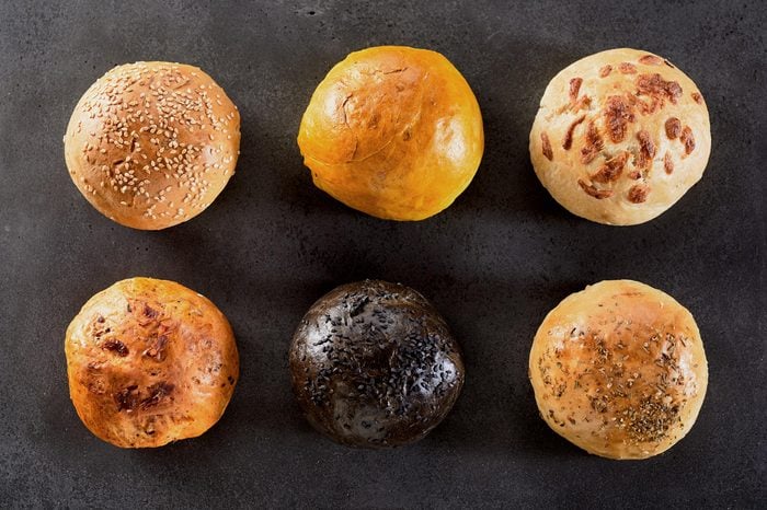 High Angle View of Variety of Six Hamburger Buns or Dinner Rolls Arranged in Two Rows on Textured Table or Counter Surface