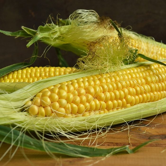 Three fresh corn cob on wooden table