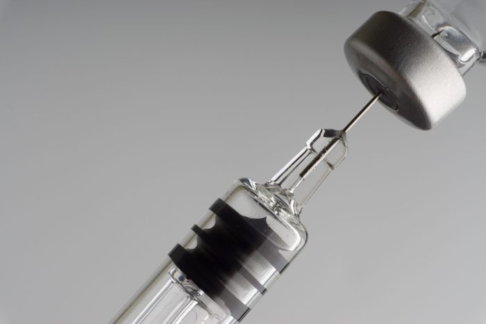 Medical syringe and vial on dark background with selective focus and crop fragment. Healthcare and medical concept
