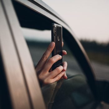 Girl takes pictures on the phone from the car window