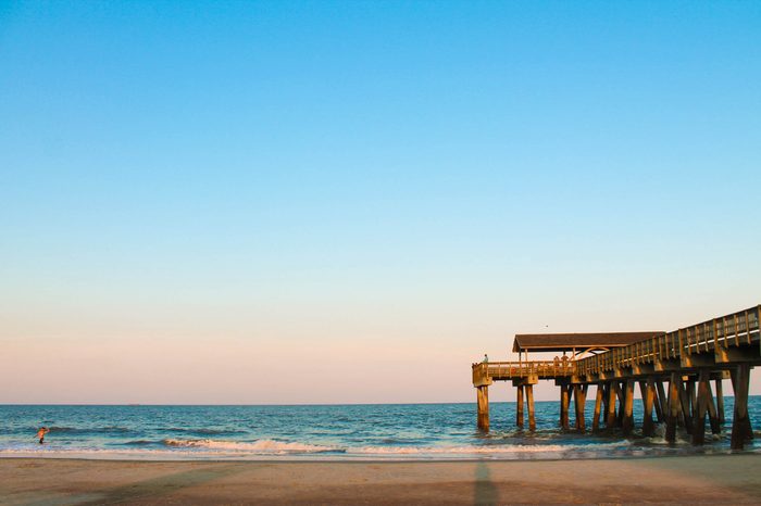 tybee island boardwalk and pier at sunset with waves crashing, bright bold colors in the sky