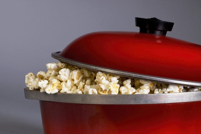 Popping popcorn the old fashion way in a red iron pot.