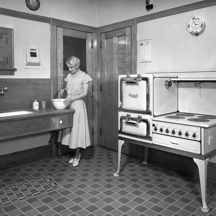 A woman cooking in her kitchen, which is equipped with a Monarch electric stove.