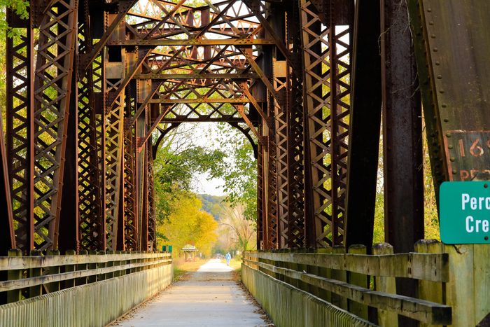 Fall view of a former railroad bridge converted into a trail in Missouri State Park in the fall; fall trees in the background
