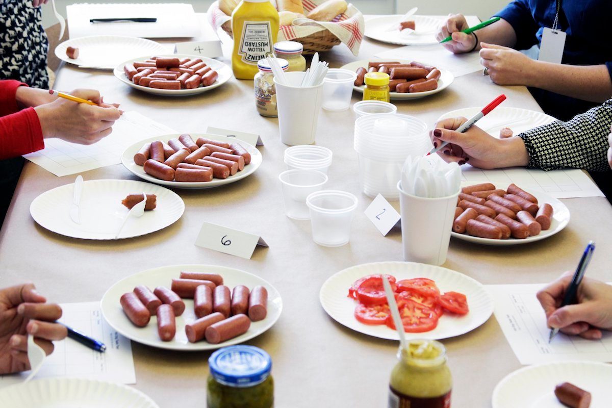 Panel of testers sampling different brands to find the best hot dog.