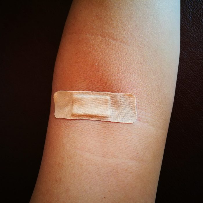 putting adhesive bandage on arm