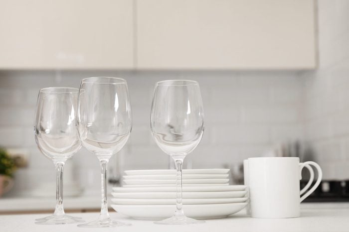 Stack of clean dishes, glasses and cups on table in kitchen