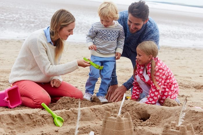 Family Building Sandcastles On Beach Together