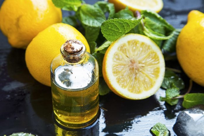 Lemon essential oil bottle with lemon fruits and mint leaves