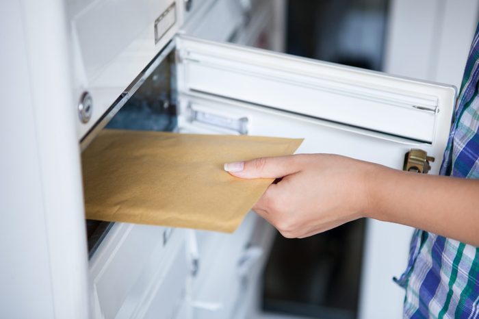 Close-up of woman's hand pulling envelop from mailbox