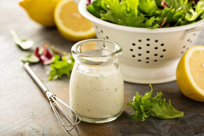 Homemade lemon ranch dressing in a small jar with fresh greens.