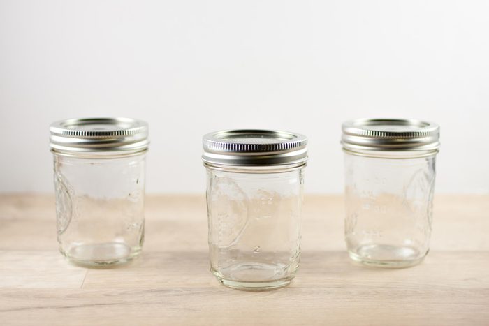 Empty canning jars sit on a wooden table.