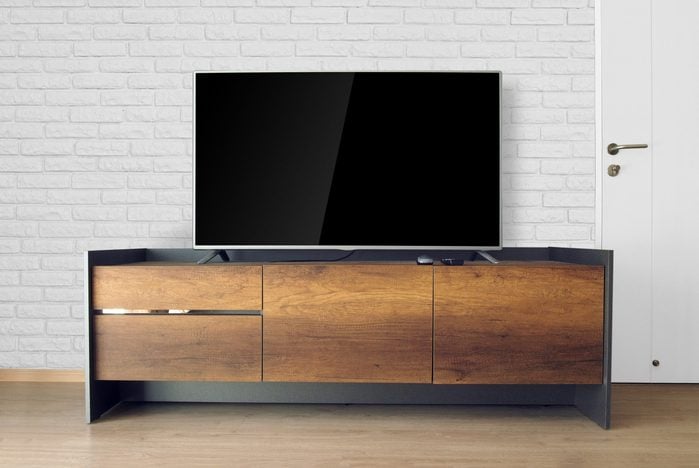 Led TV on TV stand in empty room with white brick wall. decorate in loft style.