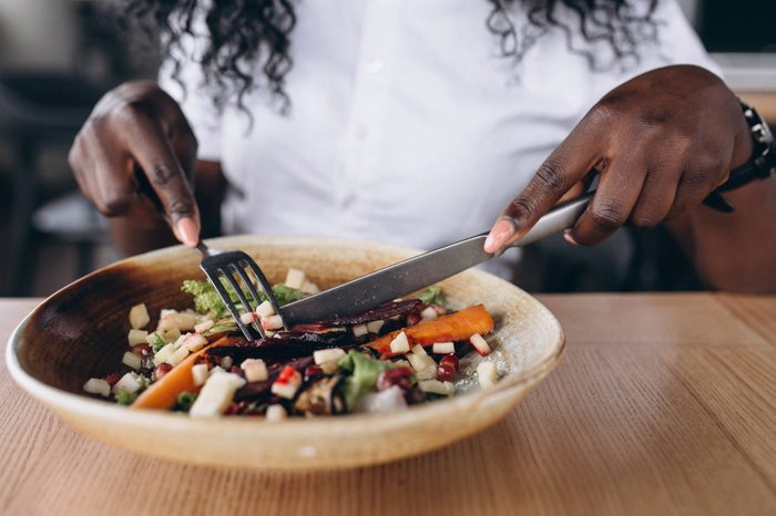 African american business woman eating salad in a cafe close up