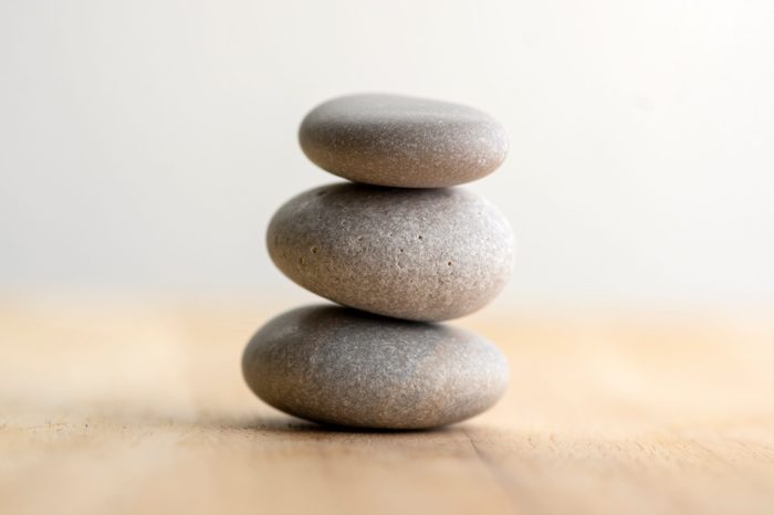 Stone cairn on striped grey white background, three stones tower, simple poise stones, simplicity harmony and balance, rock zen sculptures