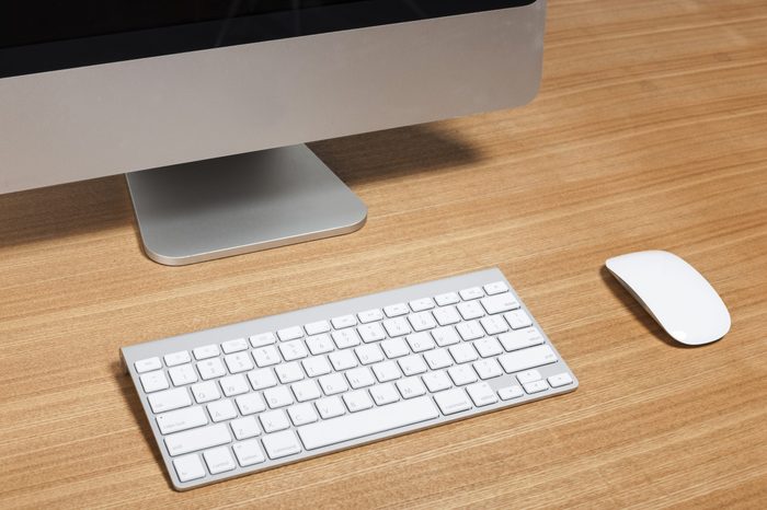 A aluminum(grey) desktop personal computer(PC) with wireless keyboard, mouse on the wood table(desk) isolated white.