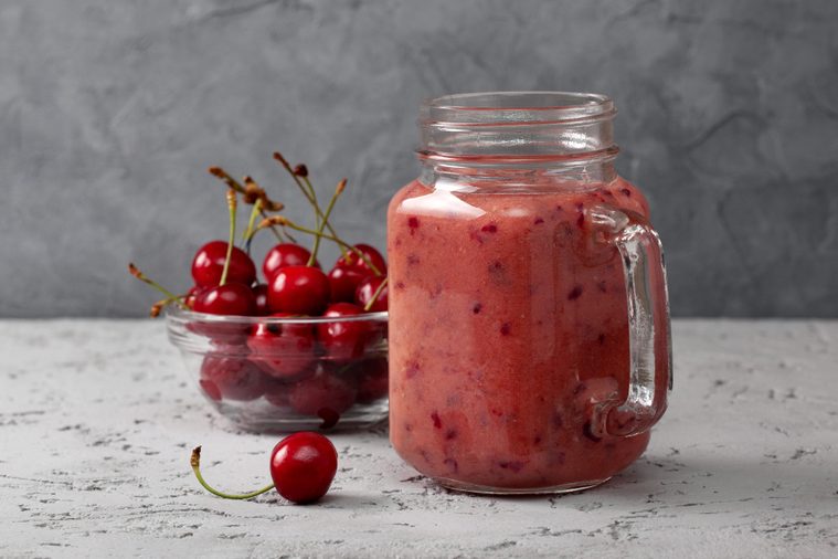 cherry smoothie in Mason jar on a gray concrete background