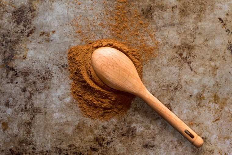 ground cinnamon spilled out of a wooden spoon