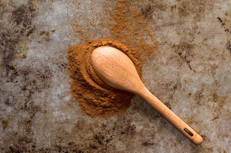 ground cinnamon spilled out of a wooden spoon
