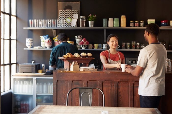 Staff Serving Customer In Busy Coffee Shop