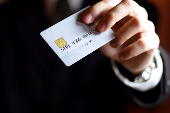 Business man presenting his credit card. Shallow DOF, focus on chip o card. Concept: Shopping and spending.