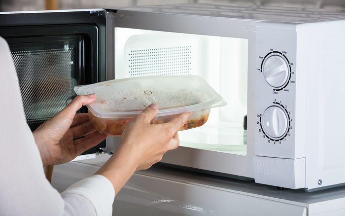 Close-up Of A Person Removing Prepared Food From Microwave Oven