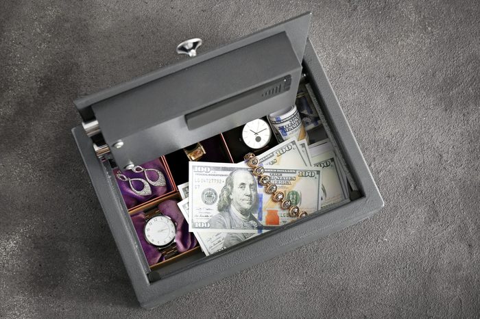 Small modern safe with valuables on grey background