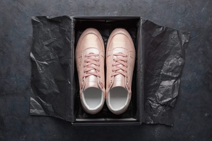 Pair of pink sneakers in shoe cardboard box on black background. Active running (walking) footwear.