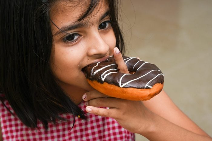 Young Indian girl child eating her chocolate doughnut or donut Mumbai, India.